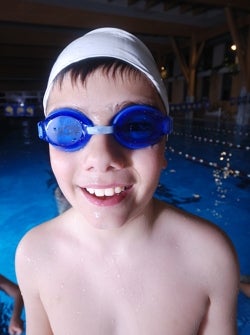 Gutt med svømmebriller foran svømmebasseng